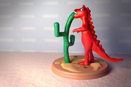 Figurine de dinosaure rouge qui mange un cactus.